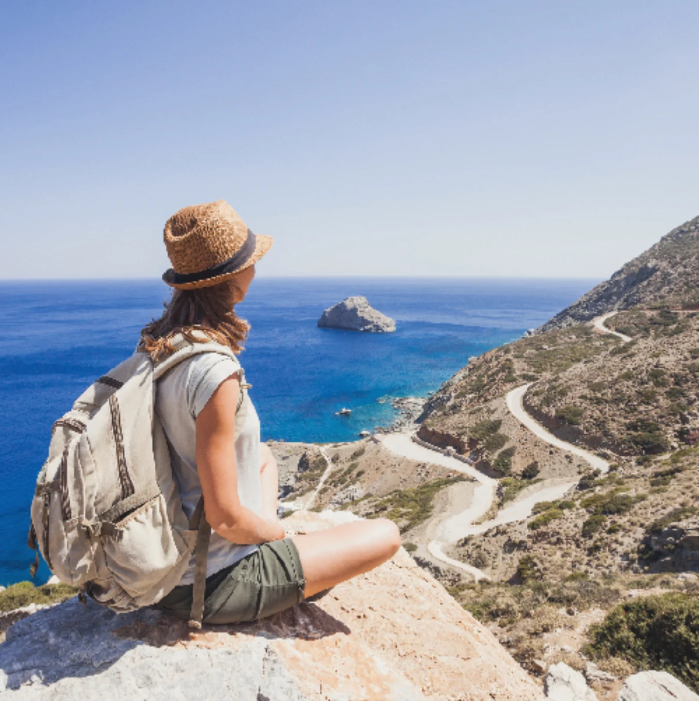 Mujer viajera con mochila observando el mar